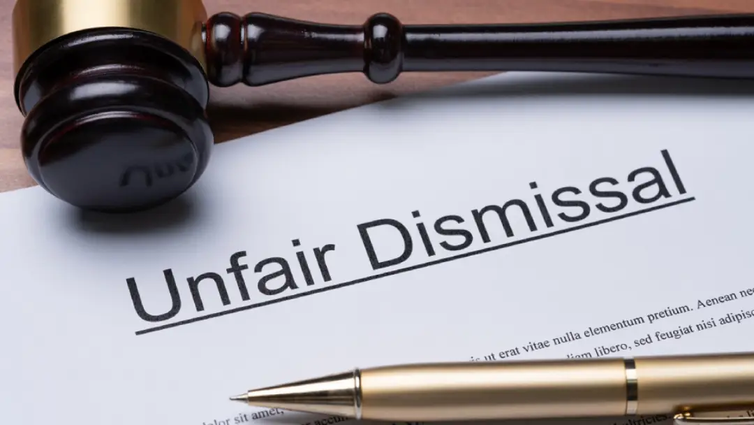 Studio image of a judge's hammer laid across paper with the words unfair dismissal.