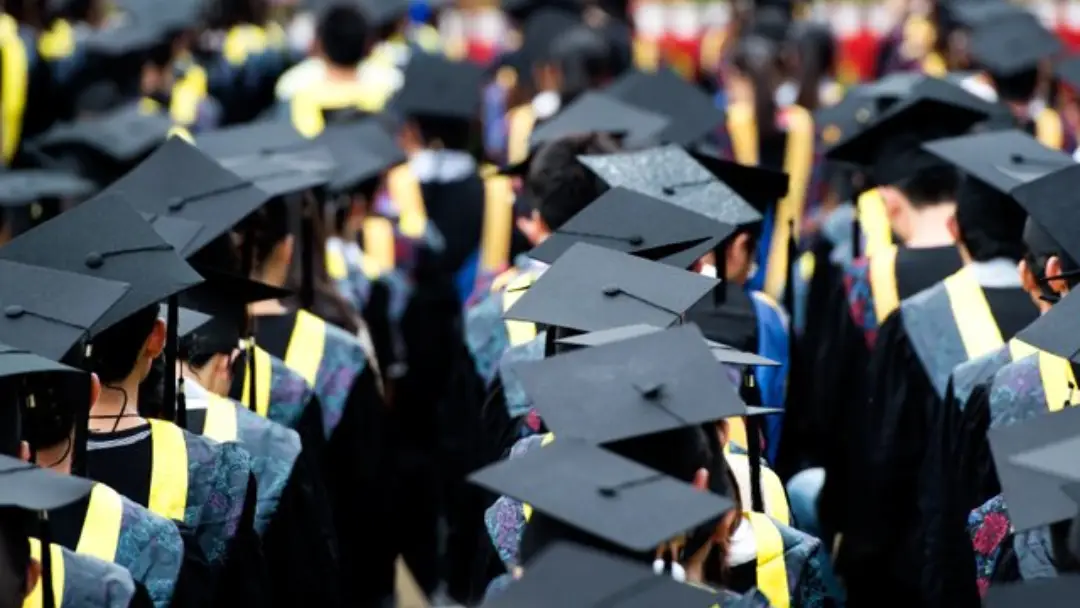 Image of university students standing in line with a mortarboard hat