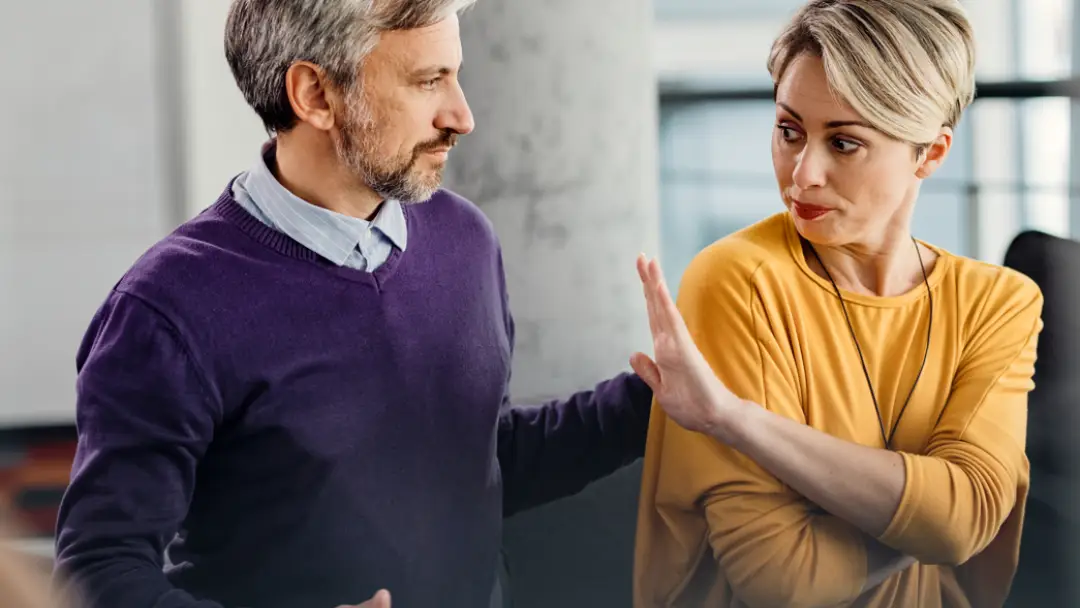 Image of two persons with one person holding their hand in a gesture to say stop or no in a duty to prevent sexual harassment.