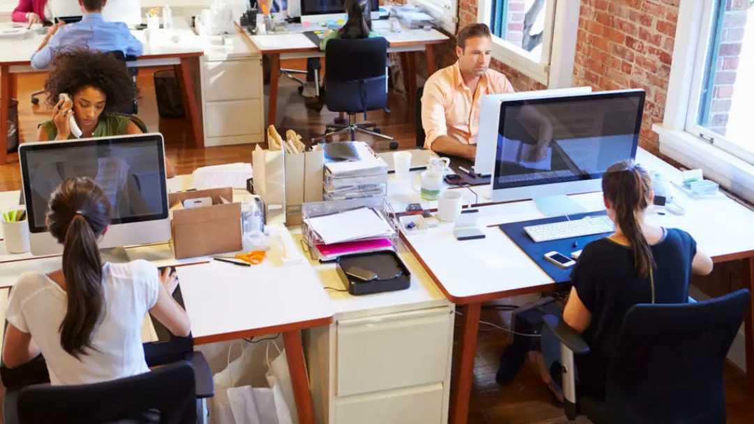 The scene depicts an office setting, where employees are arranged around their personal workstations. Discussing tribunal awards.