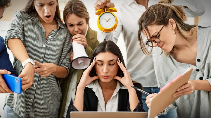 The image shows a crowd of people gathered behind a visibly stressed worker. The image depicts stress at work and the obligations of an employer.