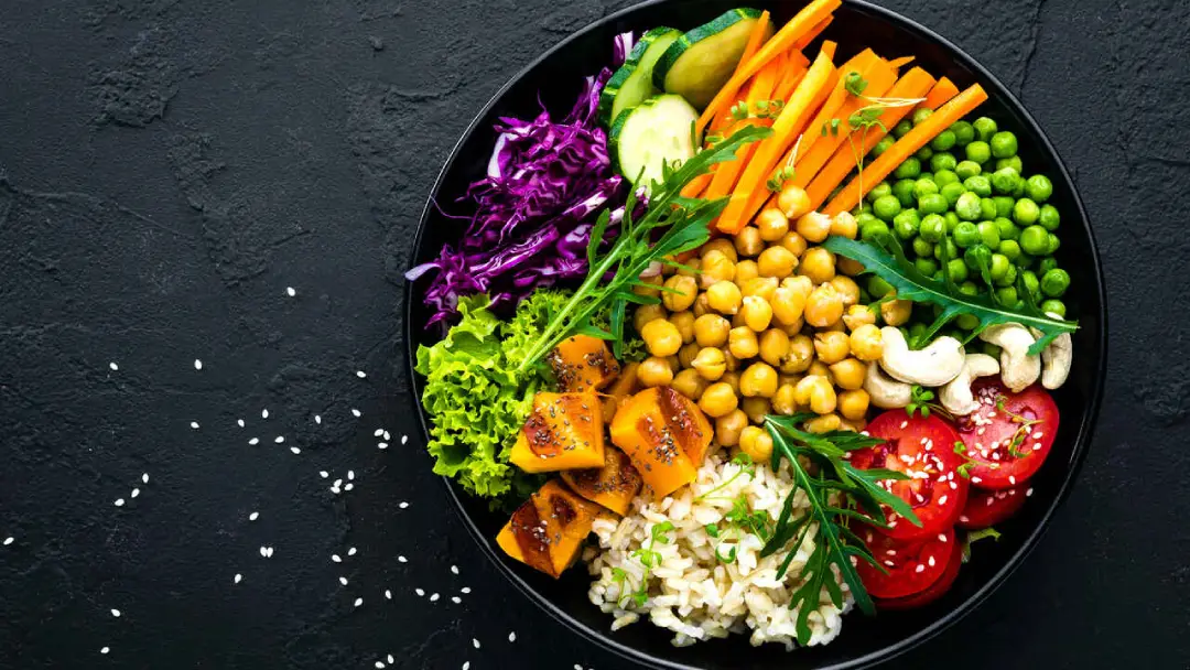A studio image of a bowl of healthy-looking salad ingredients. Sitting on a black slate type table.